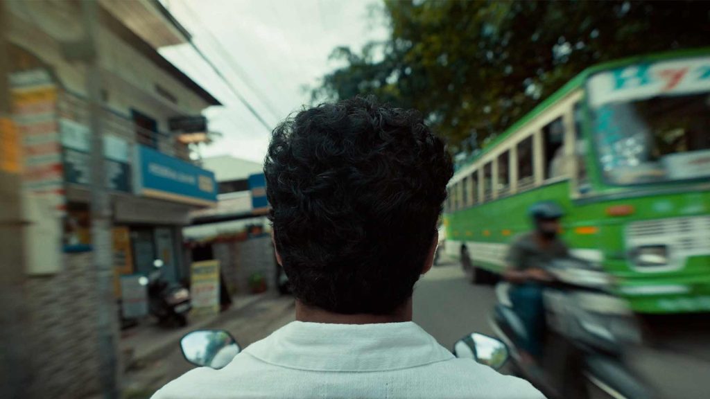 A view of a man riding on a motorcycle through the streets of Kochi India.