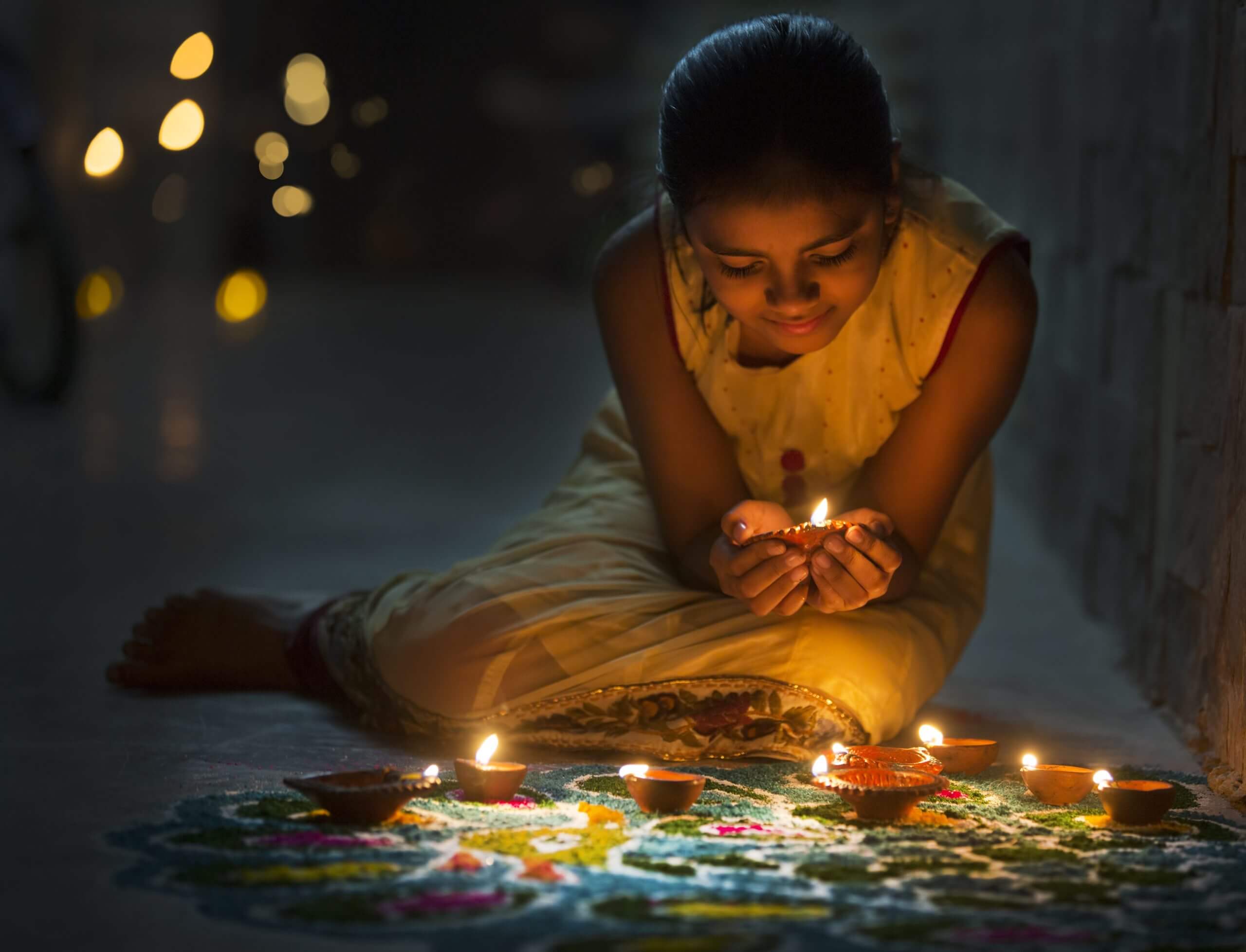 A Little girl making Rangoli and decorating with Oil lamps for Diwali celebration in India.